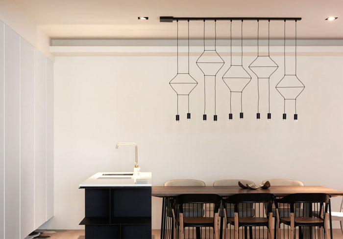 Veličastna viseča svetilka Wireflow by Vibia oblikovalca Arika Levyja osvetljuje jedilnico.